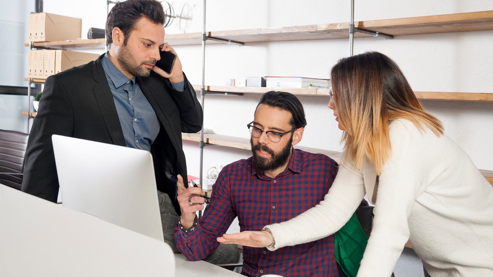 three people around a computer