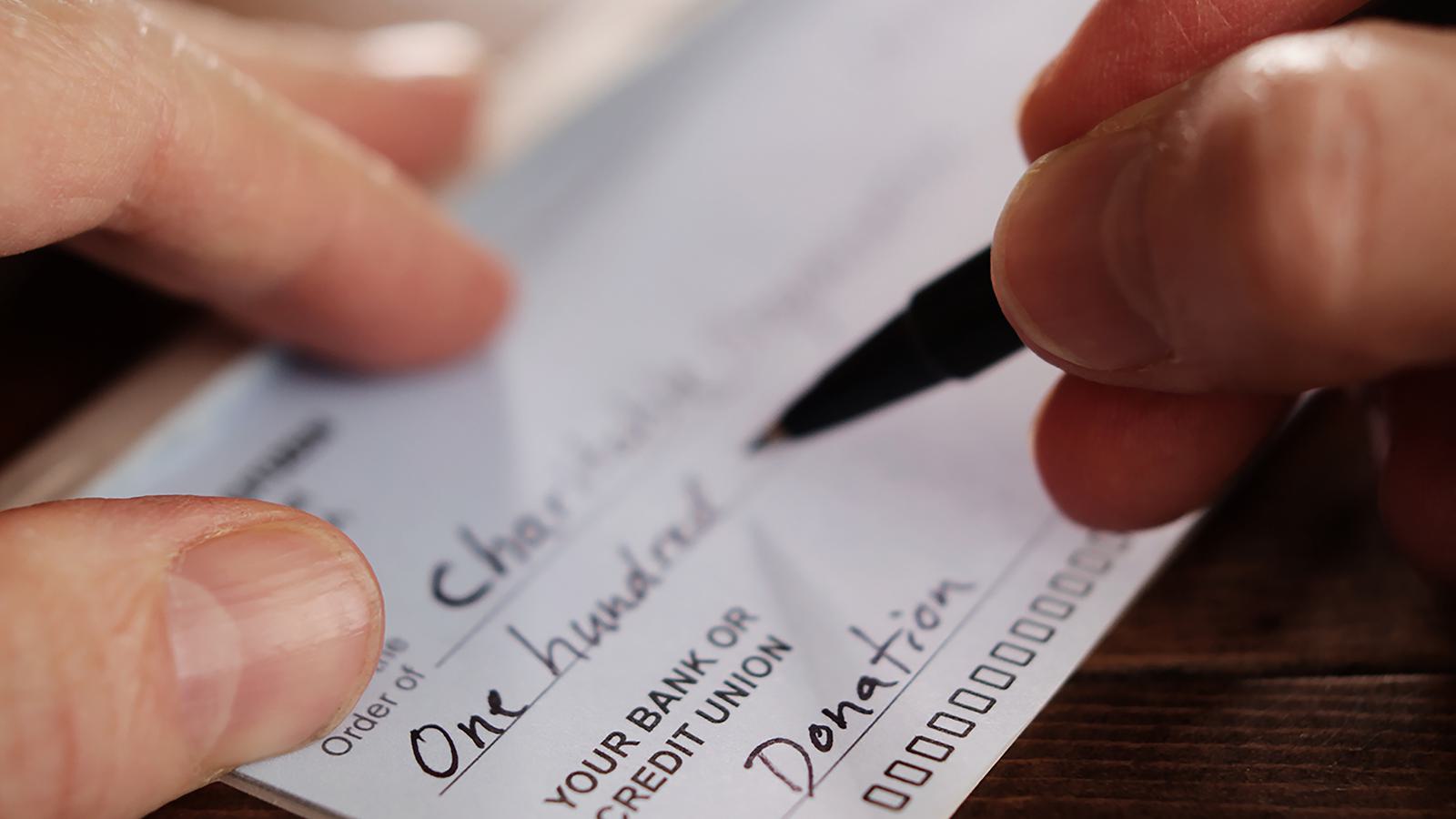 Person writing a check to a charitable organization
